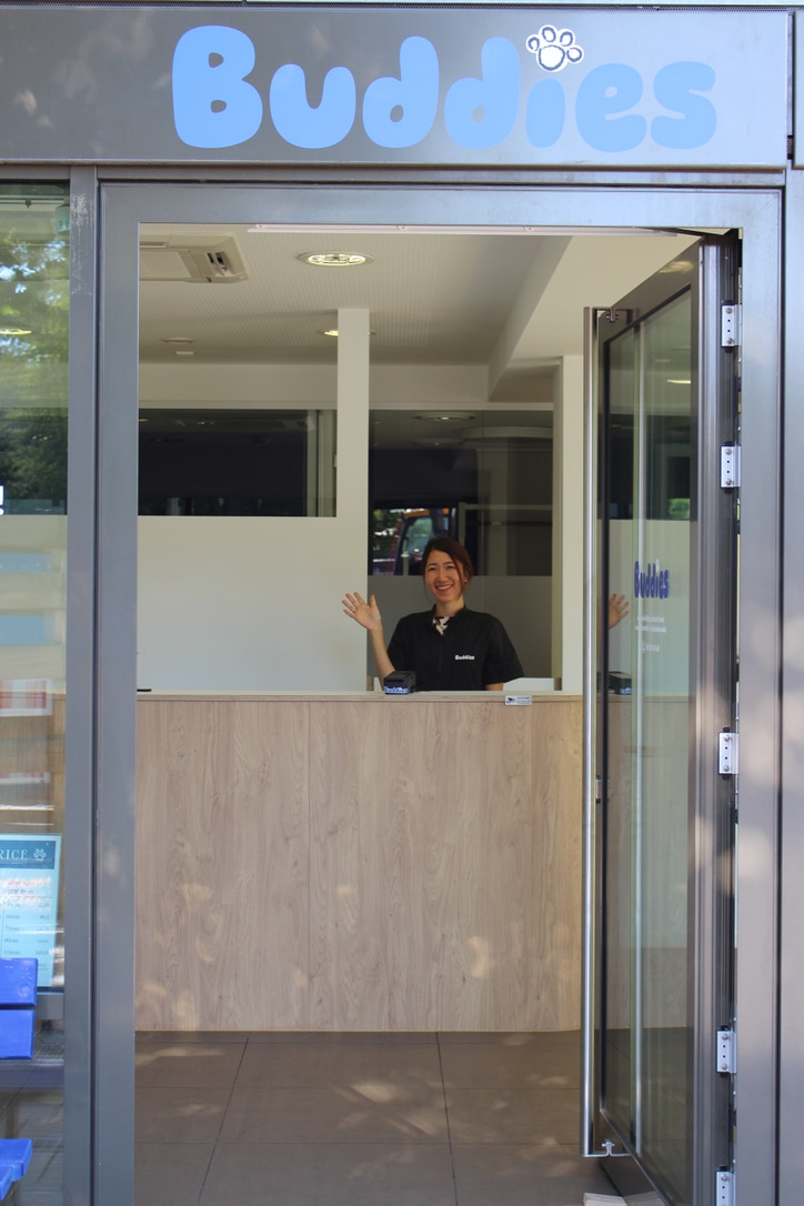 Groomerin winkt durch die offene Tür des Buddies Salons in Hadern
